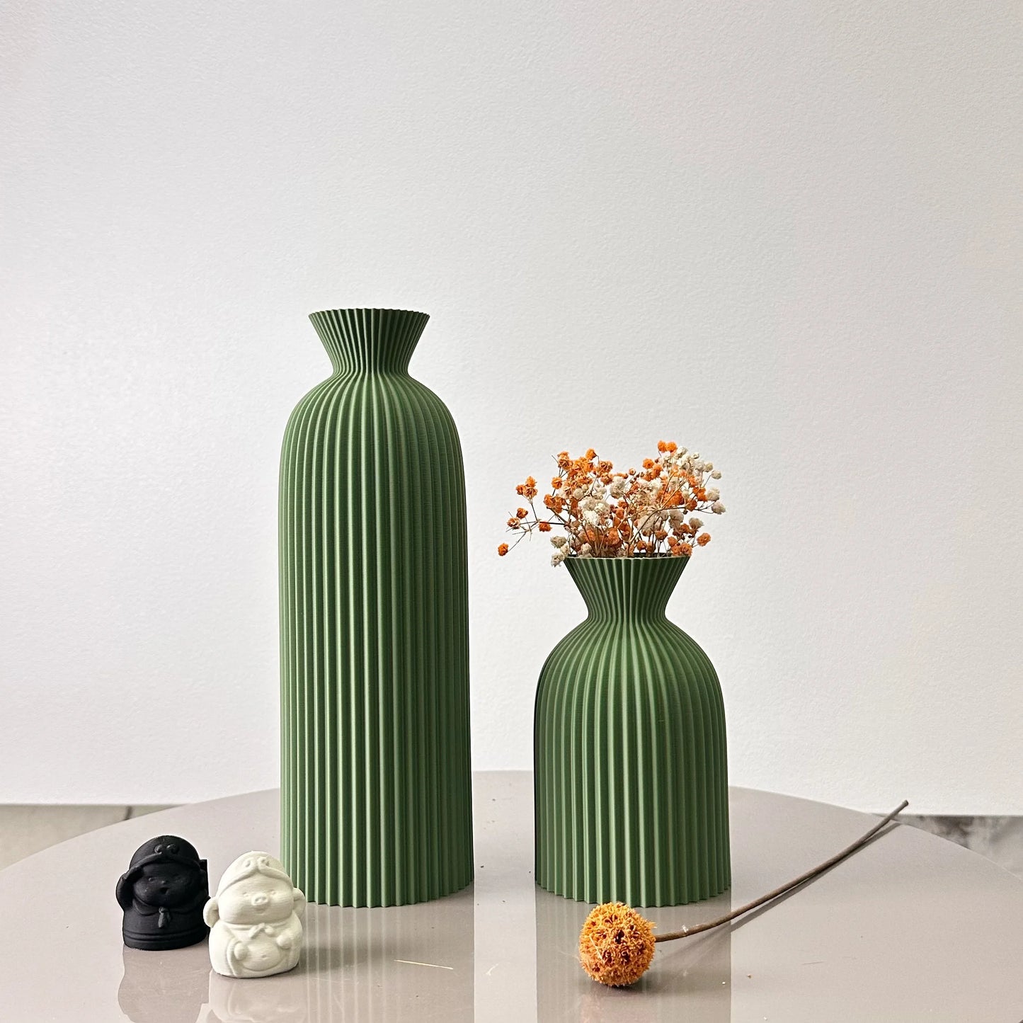 Two green textured vases on a white surface with a plain background
