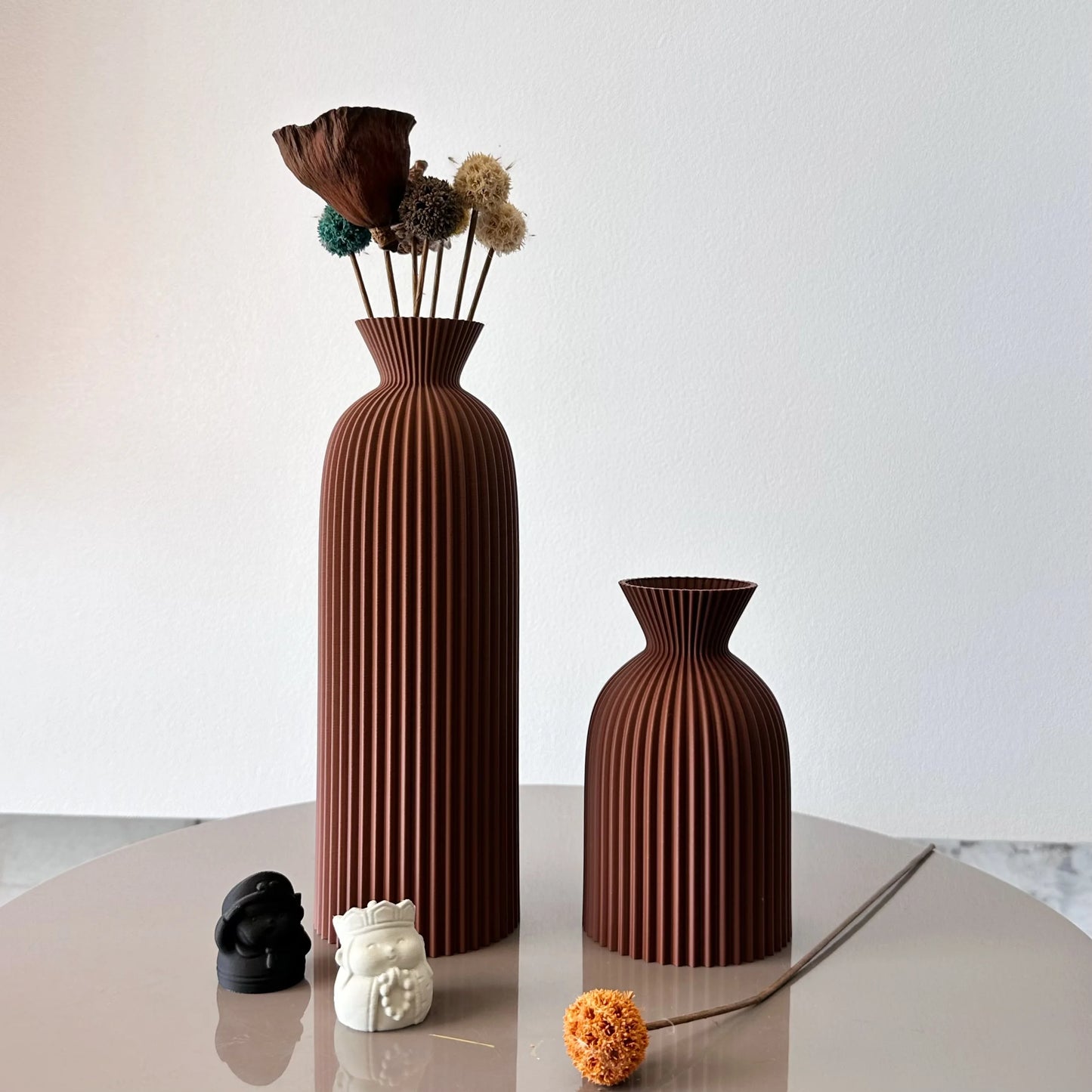 Two brown textured vases on a light surface with a white background