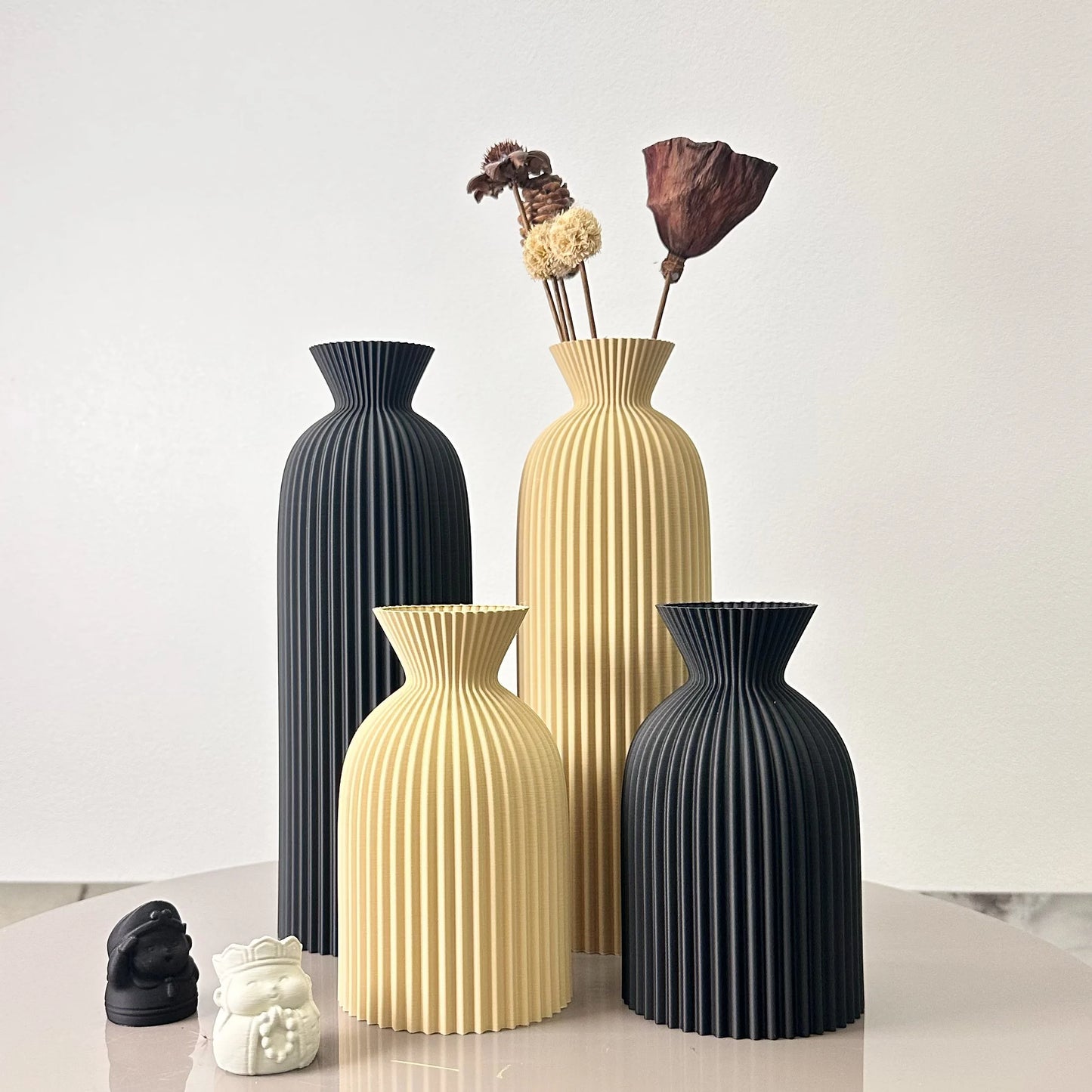 Set of four decorative vases in black and beige on a light surface with a white background