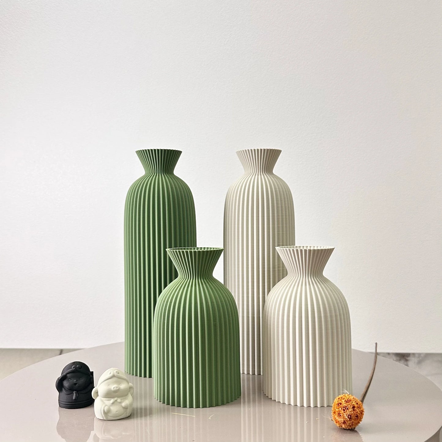 Set of four decorative vases in green and white on a light surface with a white background