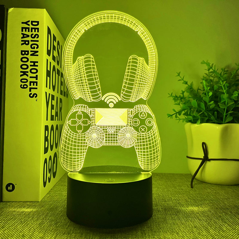 3D LED lamp shaped like a gaming controller on a green surface with a book and plant in the background.