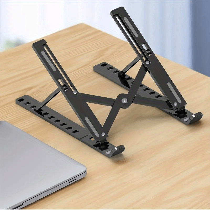 Black adjustable laptop stand on a wooden surface with a blurred background