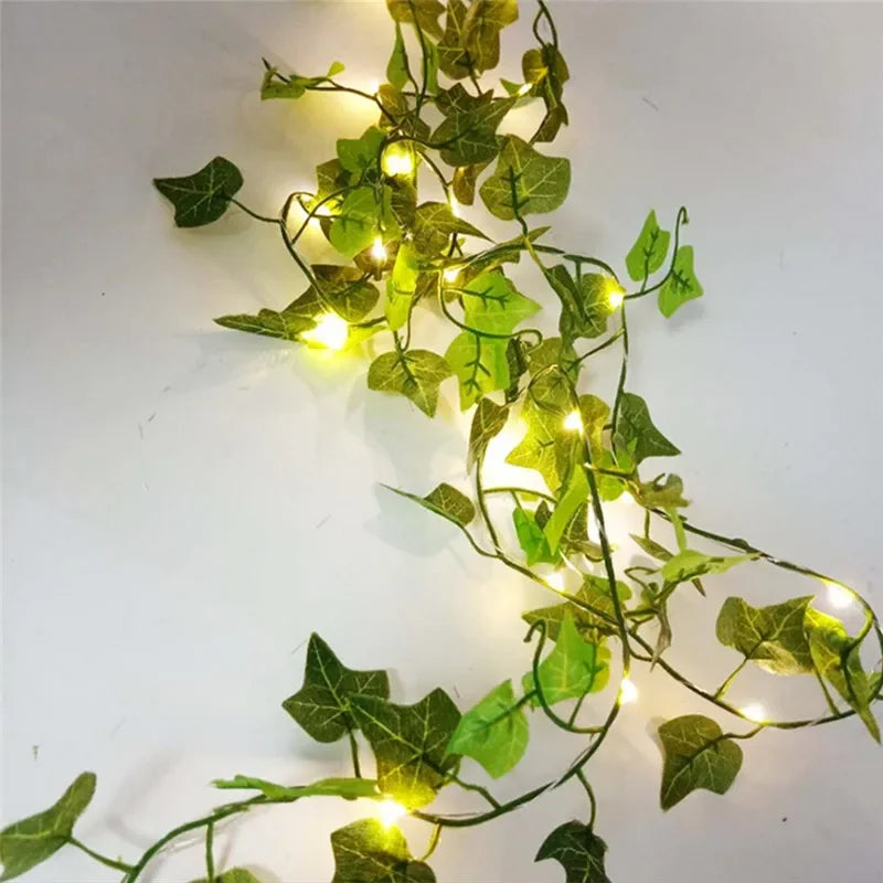 Decorative string lights with green leafy vines on a white background