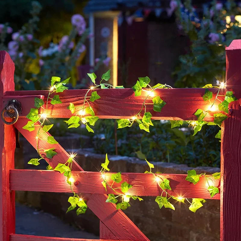 Decorative string lights with leaves on a red wooden gate at night.