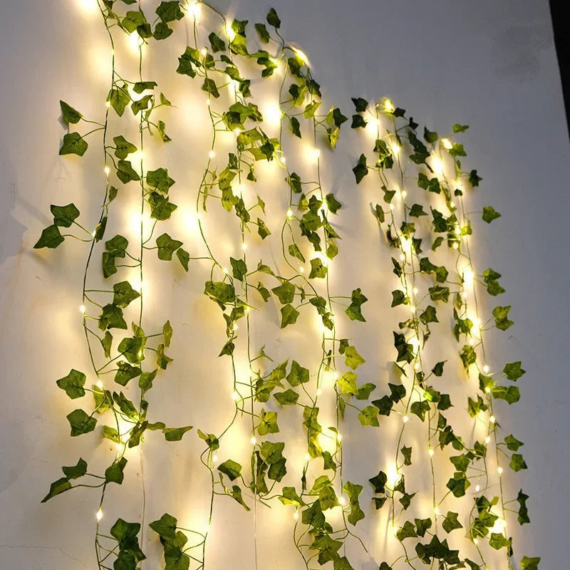 Artificial ivy leaves with string lights on a white wall