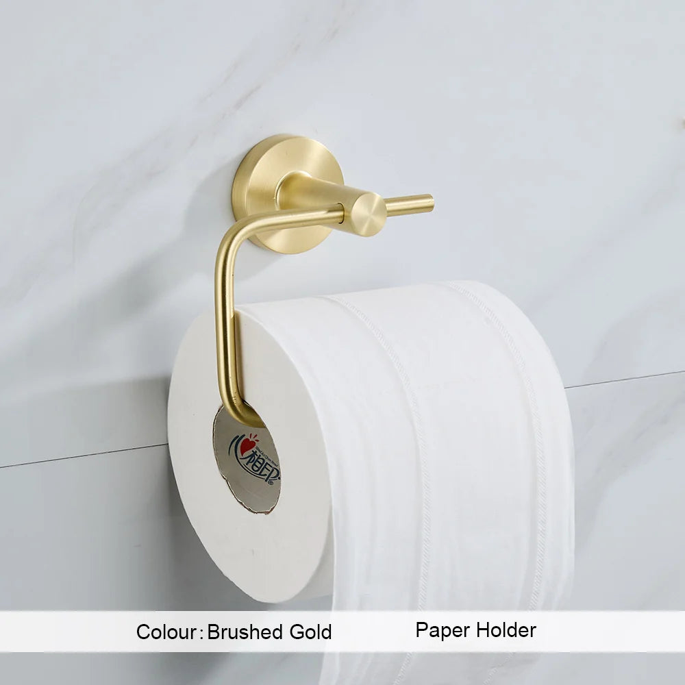 Gold toilet paper holder with a roll of toilet paper on a white tiled wall.