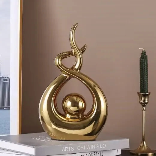 Gold decorative sculpture on a book with a candle holder in the background
