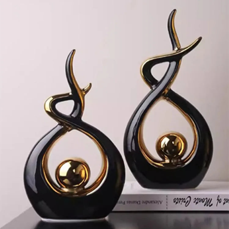 Two black and gold decorative sculptures on a white background