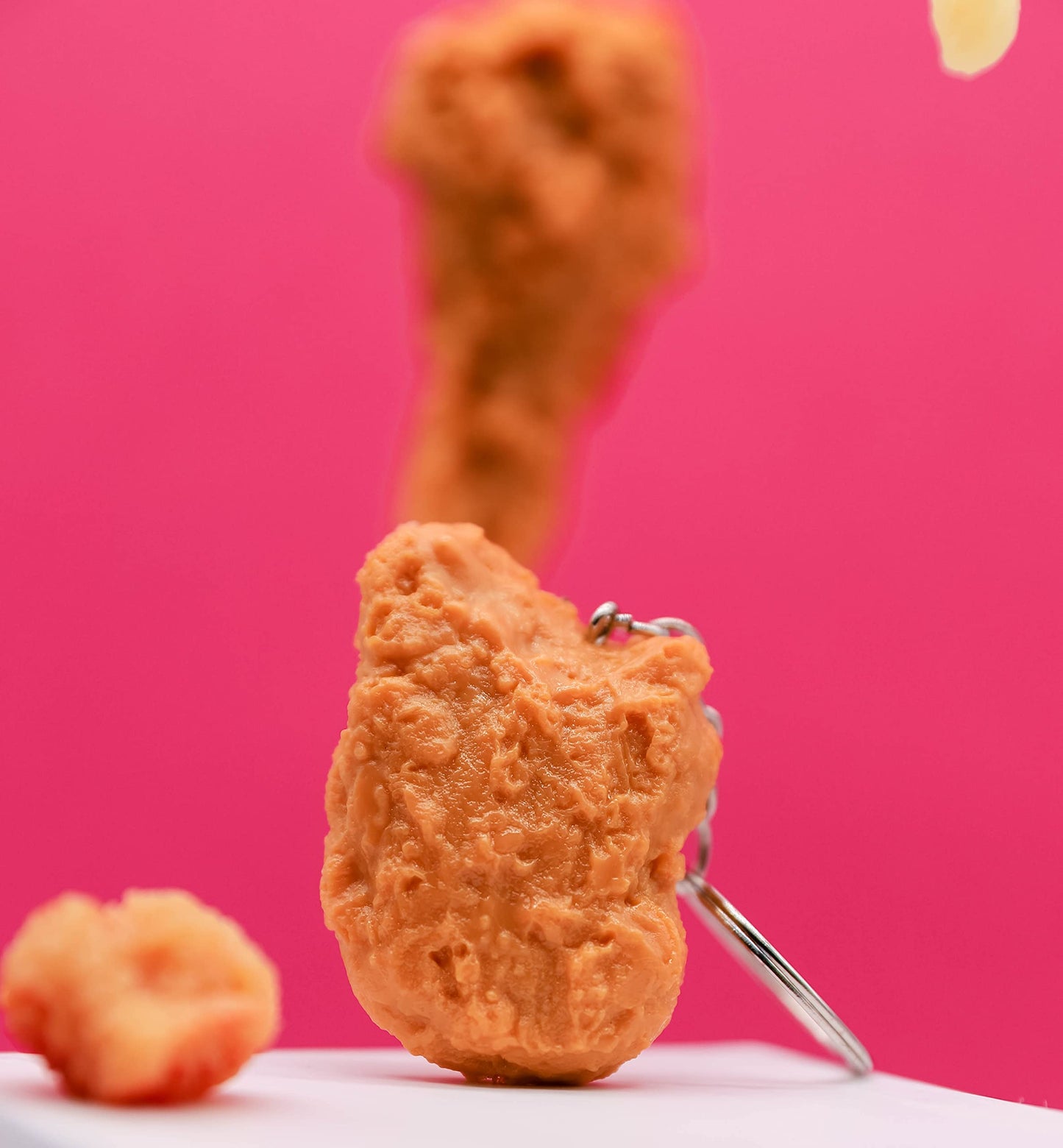 Fried chicken-shaped keychain on a pink background