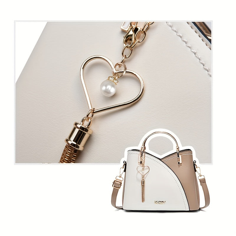 White handbag with beige accents and a heart-shaped keychain featuring a pearl on a light gray background.
