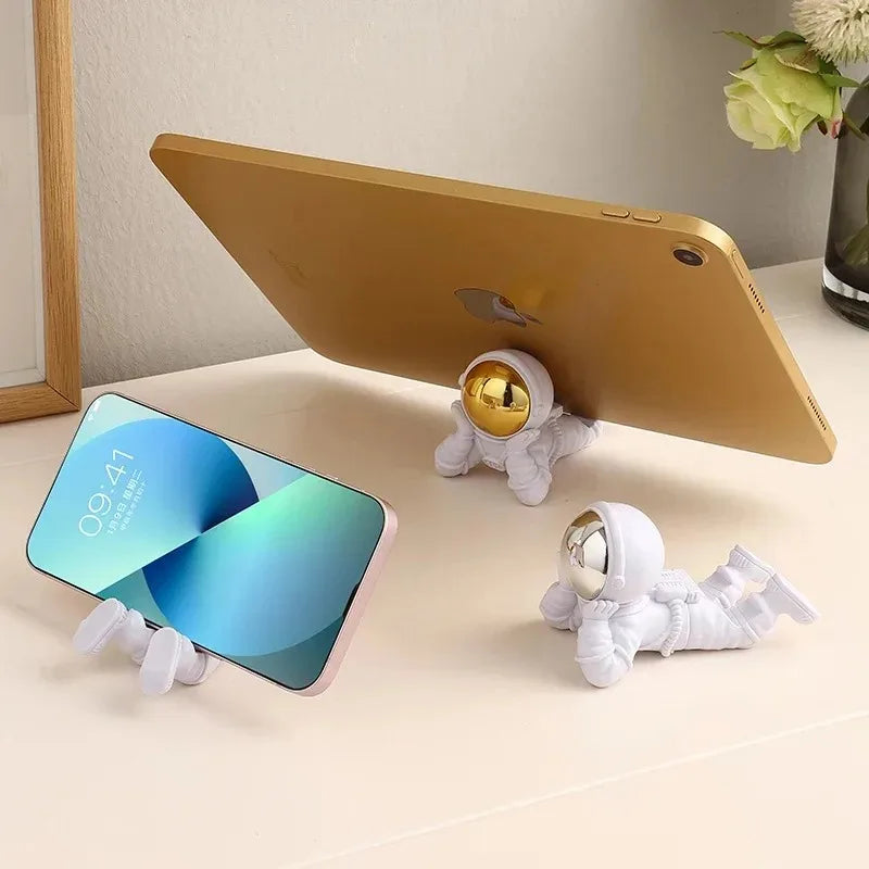 Phone holder with astronaut design holding two smartphones on a light surface.