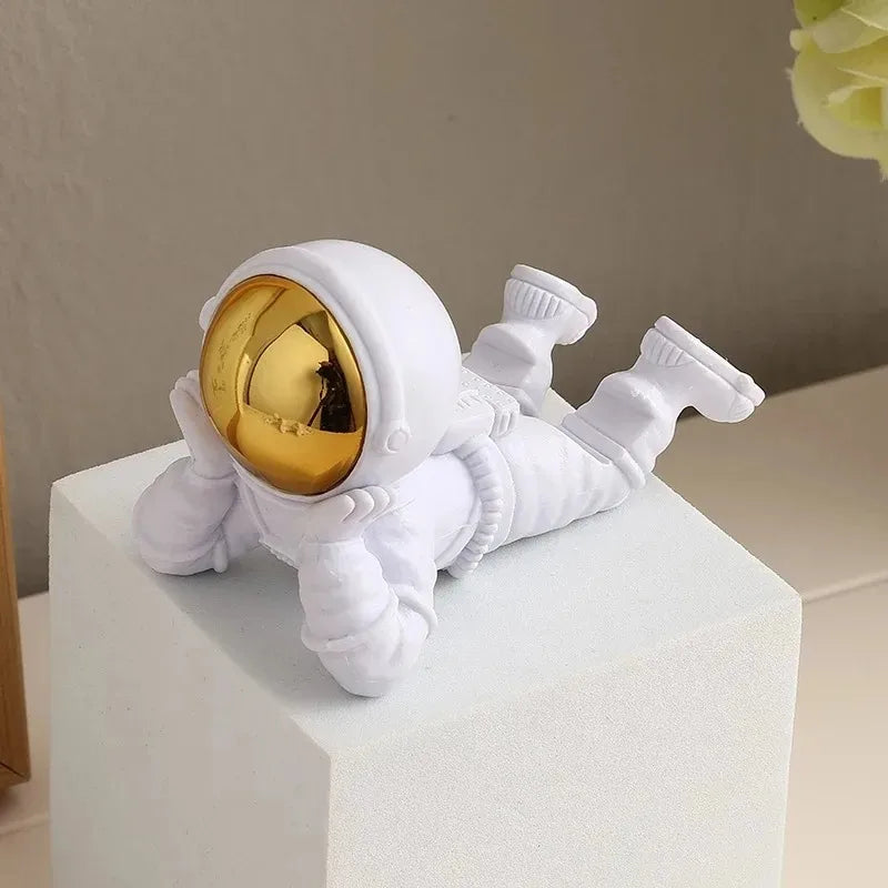 White astronaut figurine with a gold helmet on a white surface