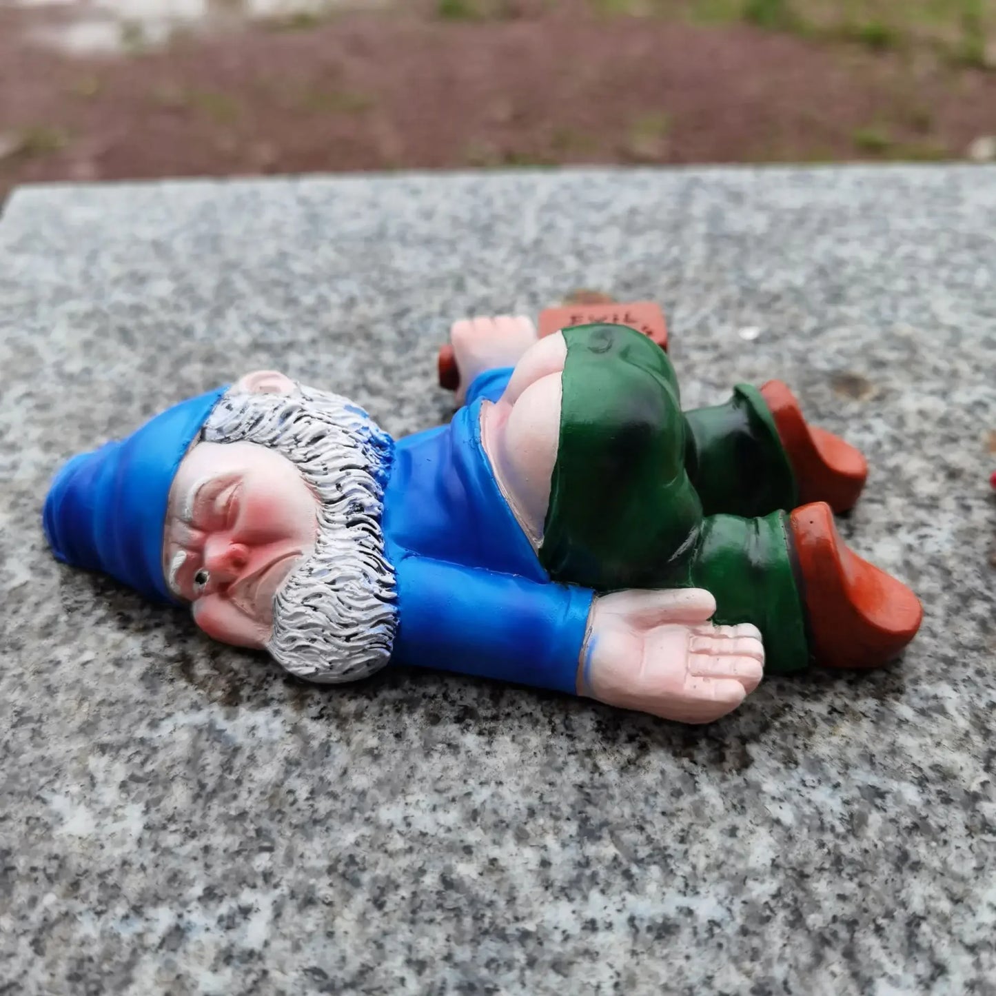 Garden gnome figurine lying on a stone surface