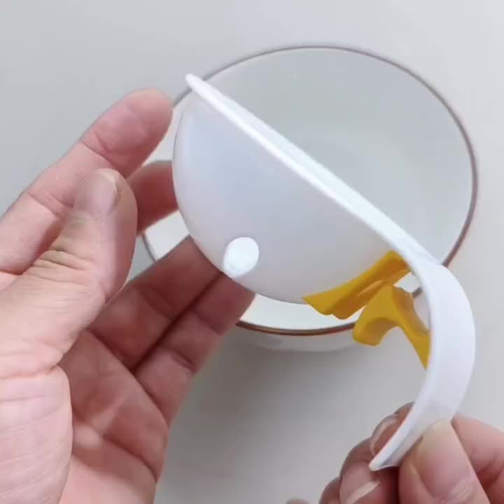White plastic tool with a yellow component held by hands against a neutral background