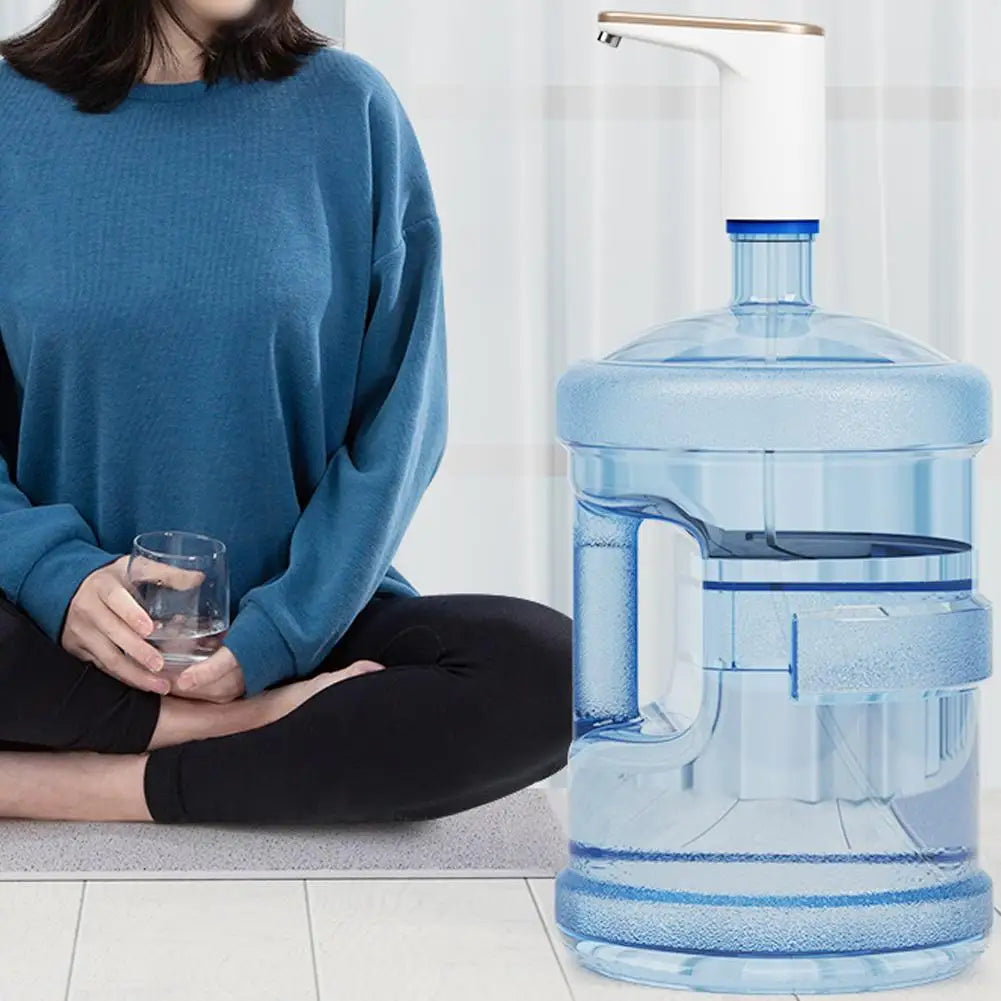 Person holding a glass of water next to a large water container indoors.