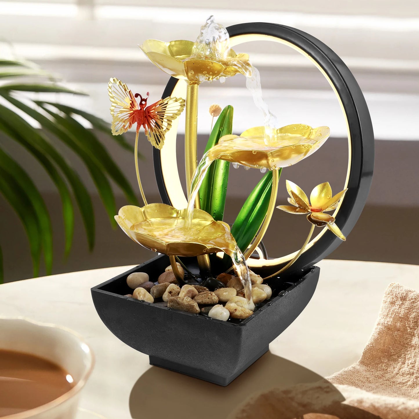 Decorative water fountain with gold lotus flowers and butterfly on a table.