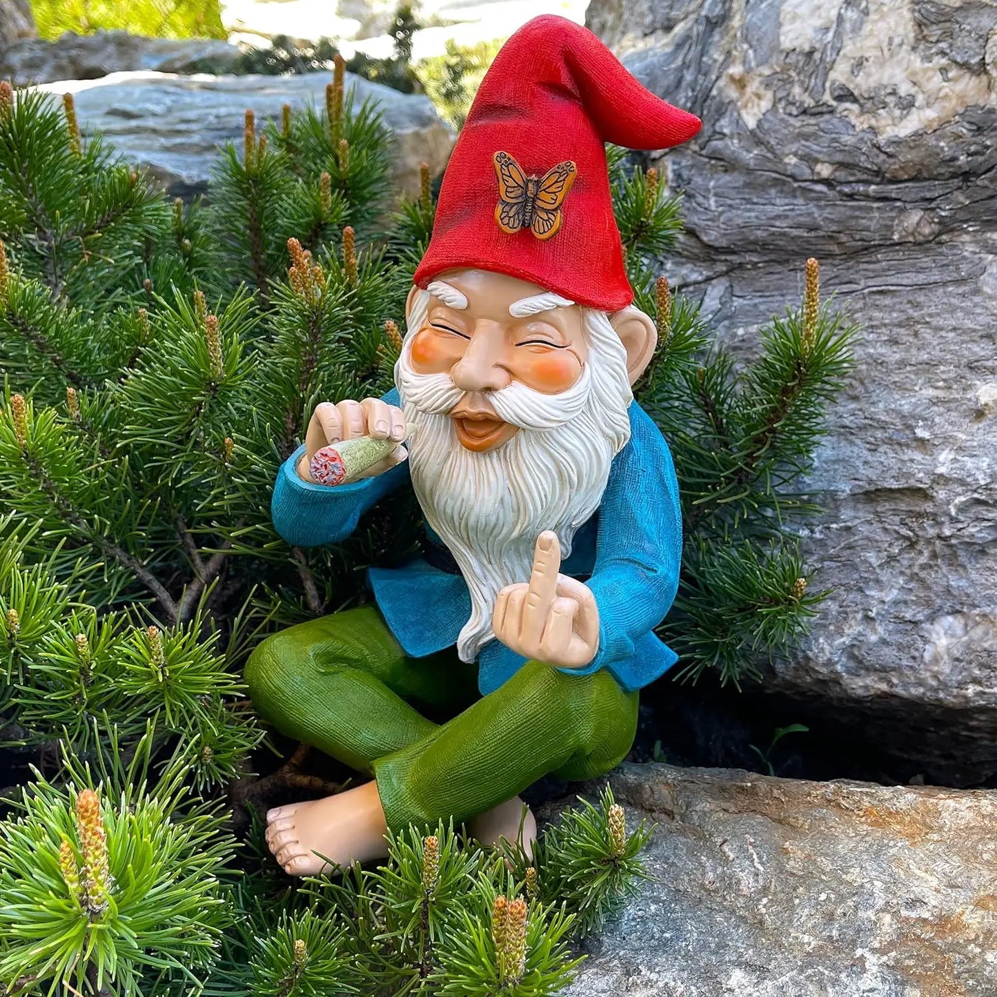 Gnome figurine with a red hat and blue coat sitting among greenery.