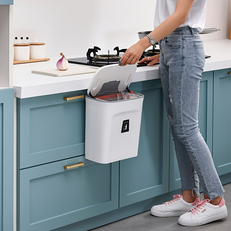Person using a wall-mounted trash can in a kitchen.