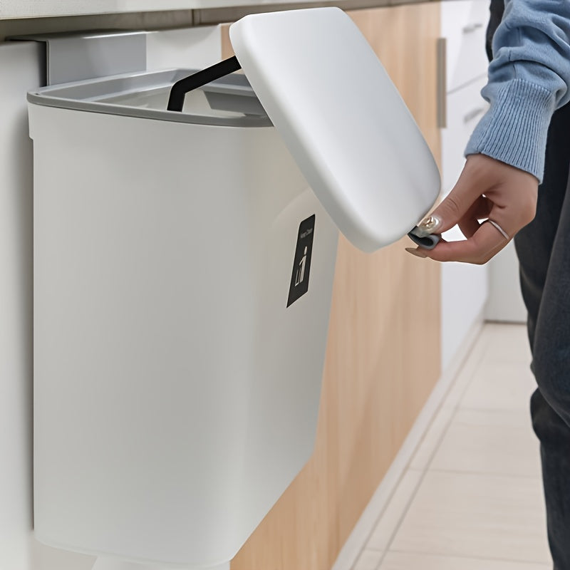 Person opening a kitchen cabinet with a trash can inside