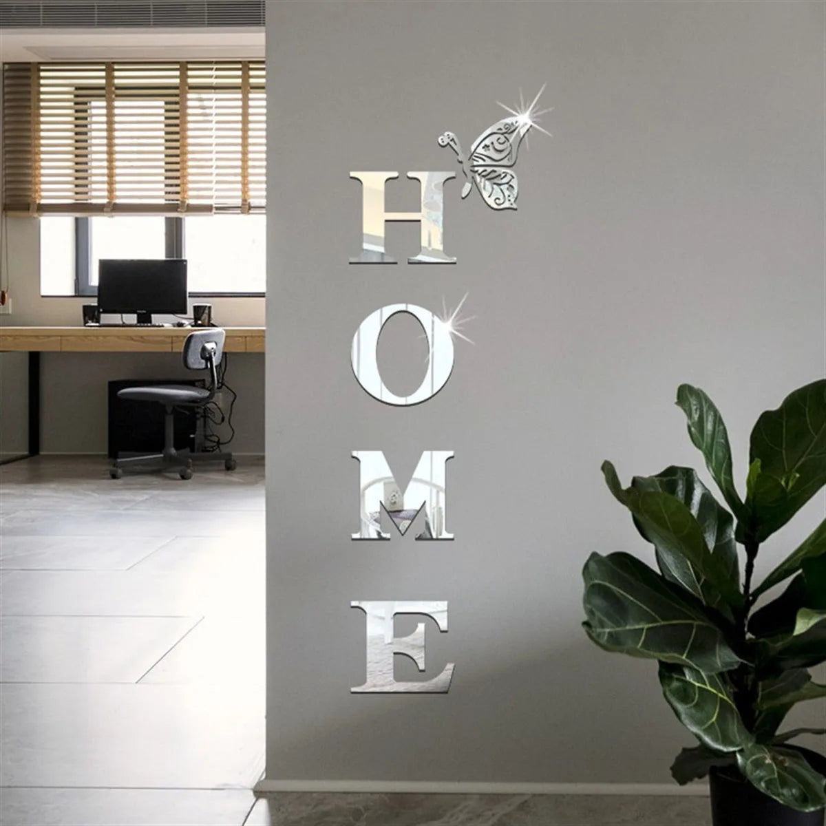 Decorative mirror letters spelling 'HOME' on a wall with a plant and office desk in the background.