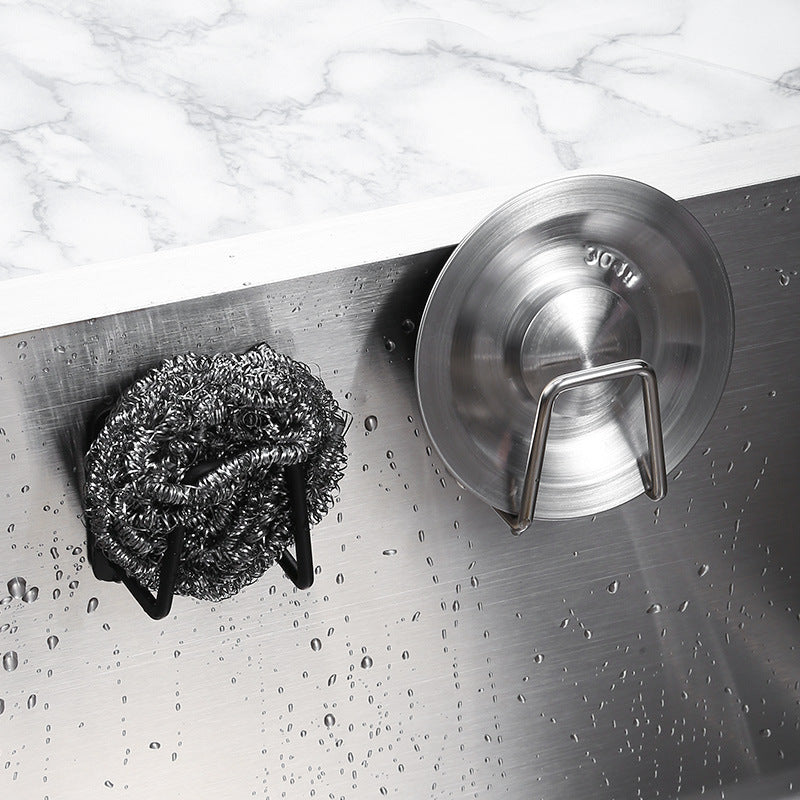 Metallic scrubber and lid lock on a metallic surface with water droplets.