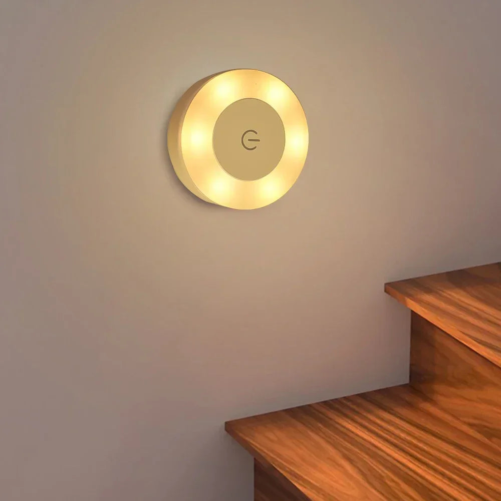 Round wall light fixture on a plain wall with a wooden shelf below.