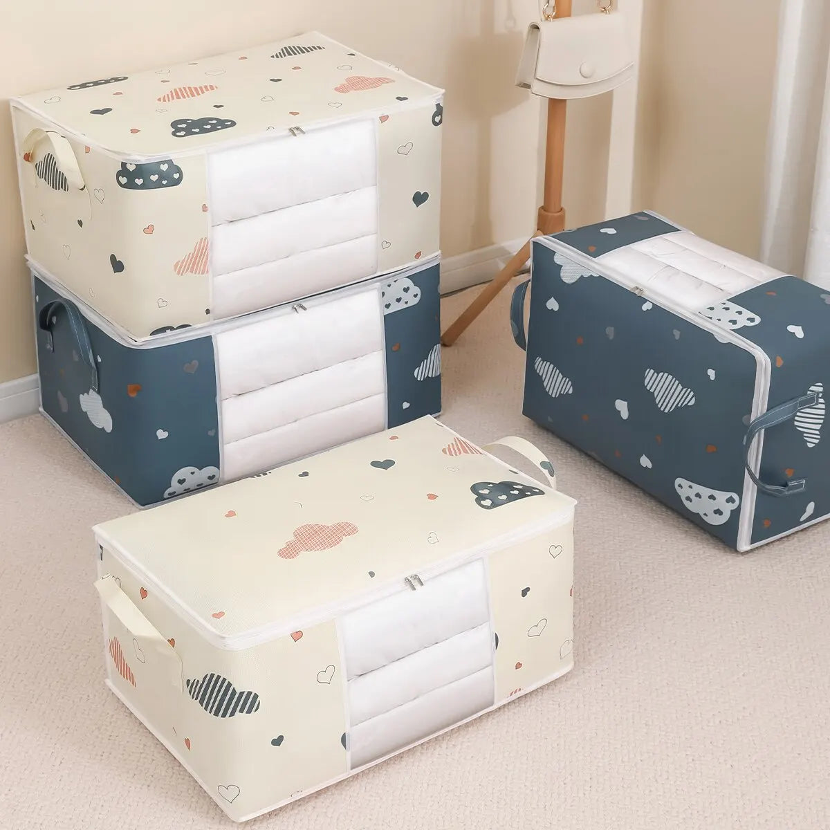 Set of three folded bedsheets in patterned storage boxes on a beige floor.