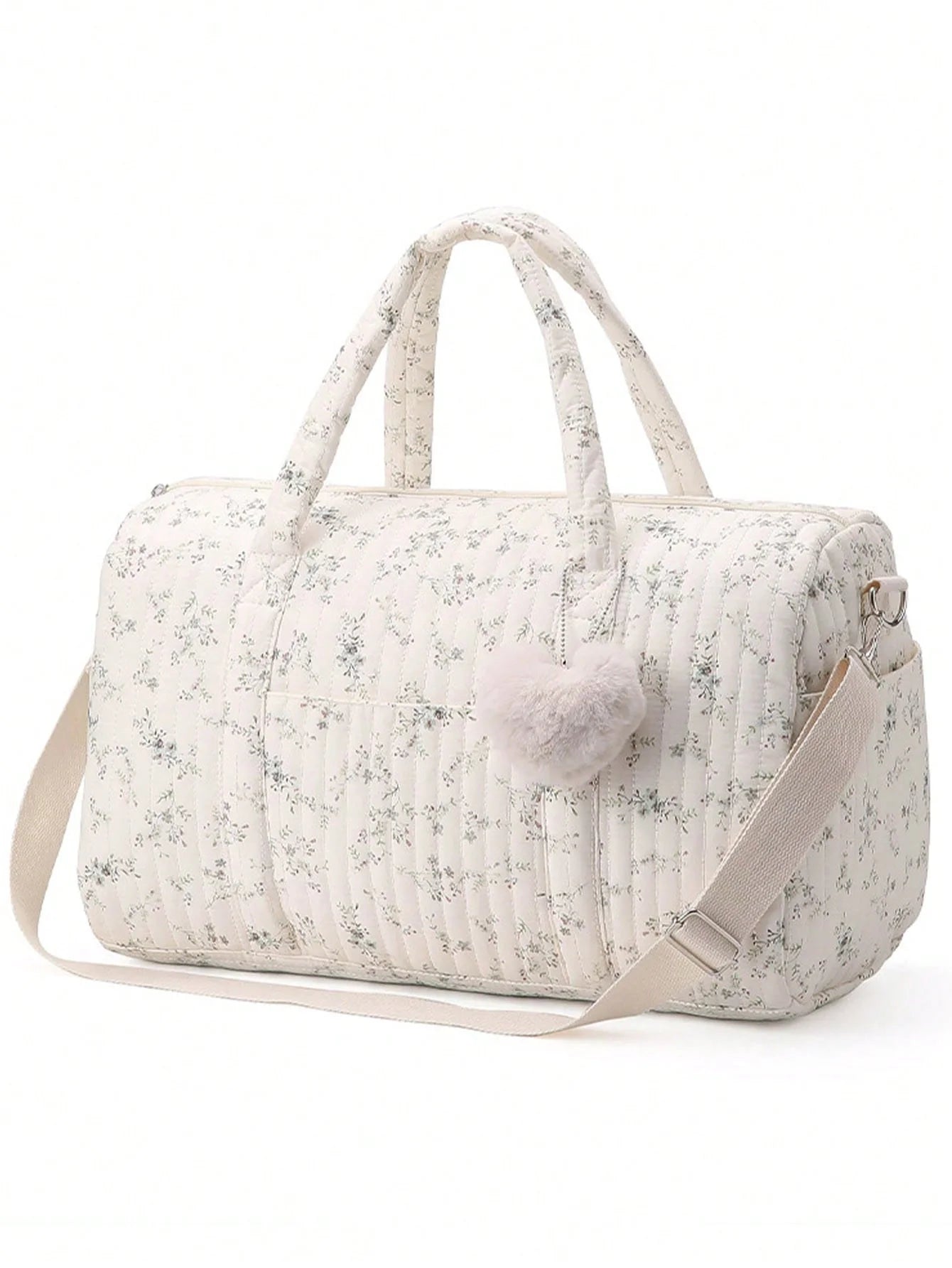 Floral patterned duffel bag with pom-pom detail on a white background