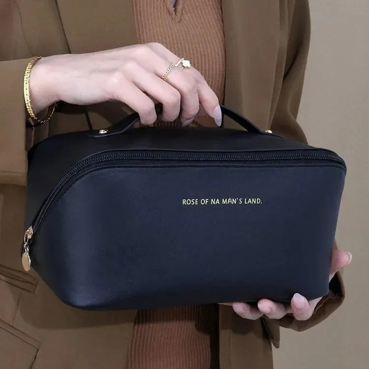 Person holding a black cosmetic bag with 'Rose of Na Man's Land' branding.