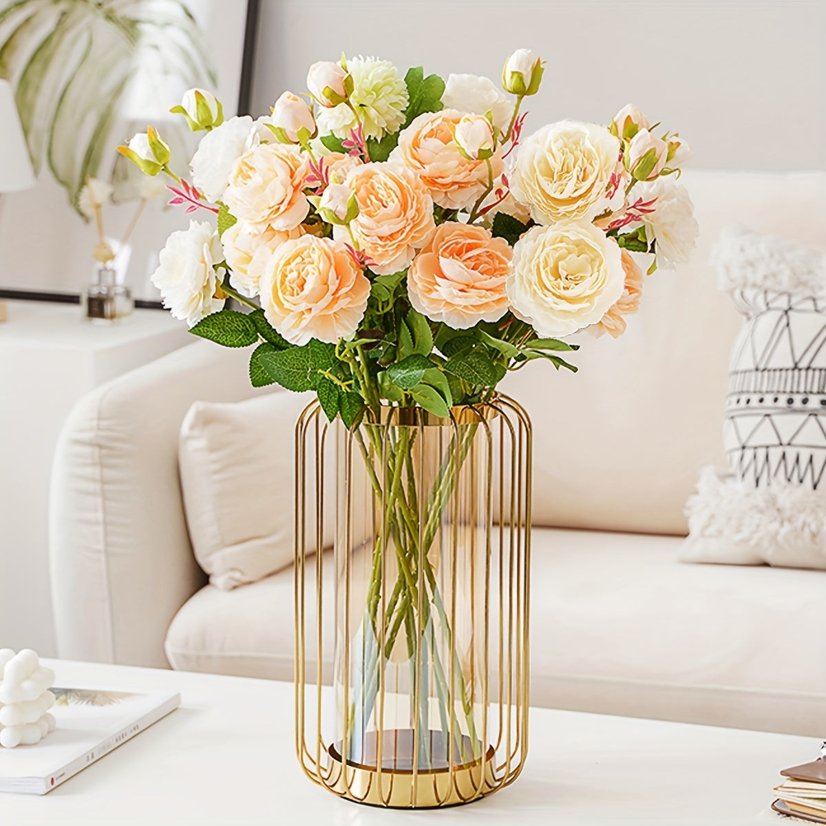 Bouquet of flowers in a gold vase on a coffee table with a white sofa in the background