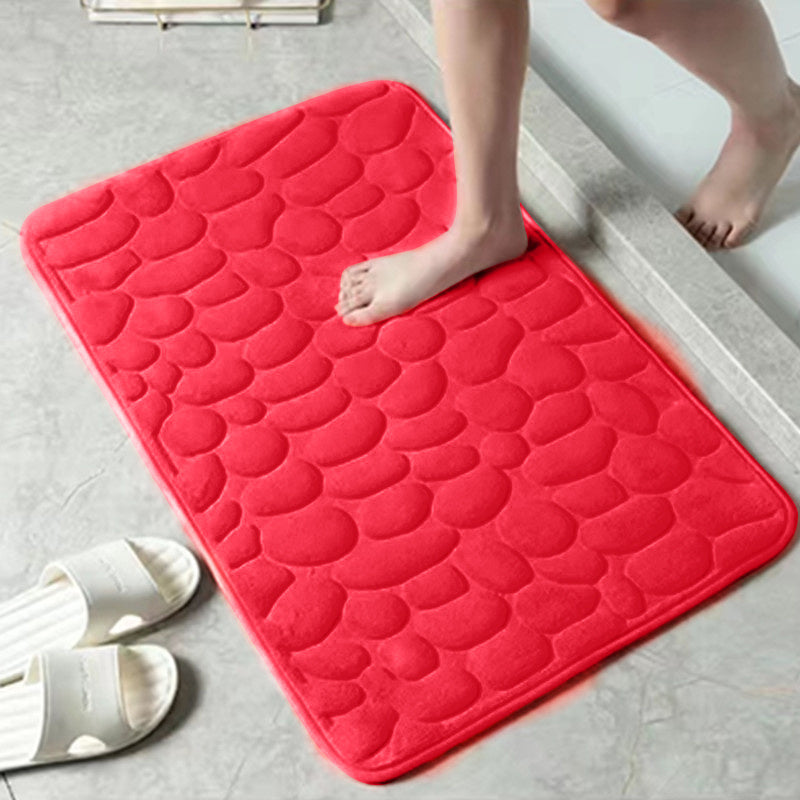 Red textured bath mat on a bathroom floor with a person stepping onto it.