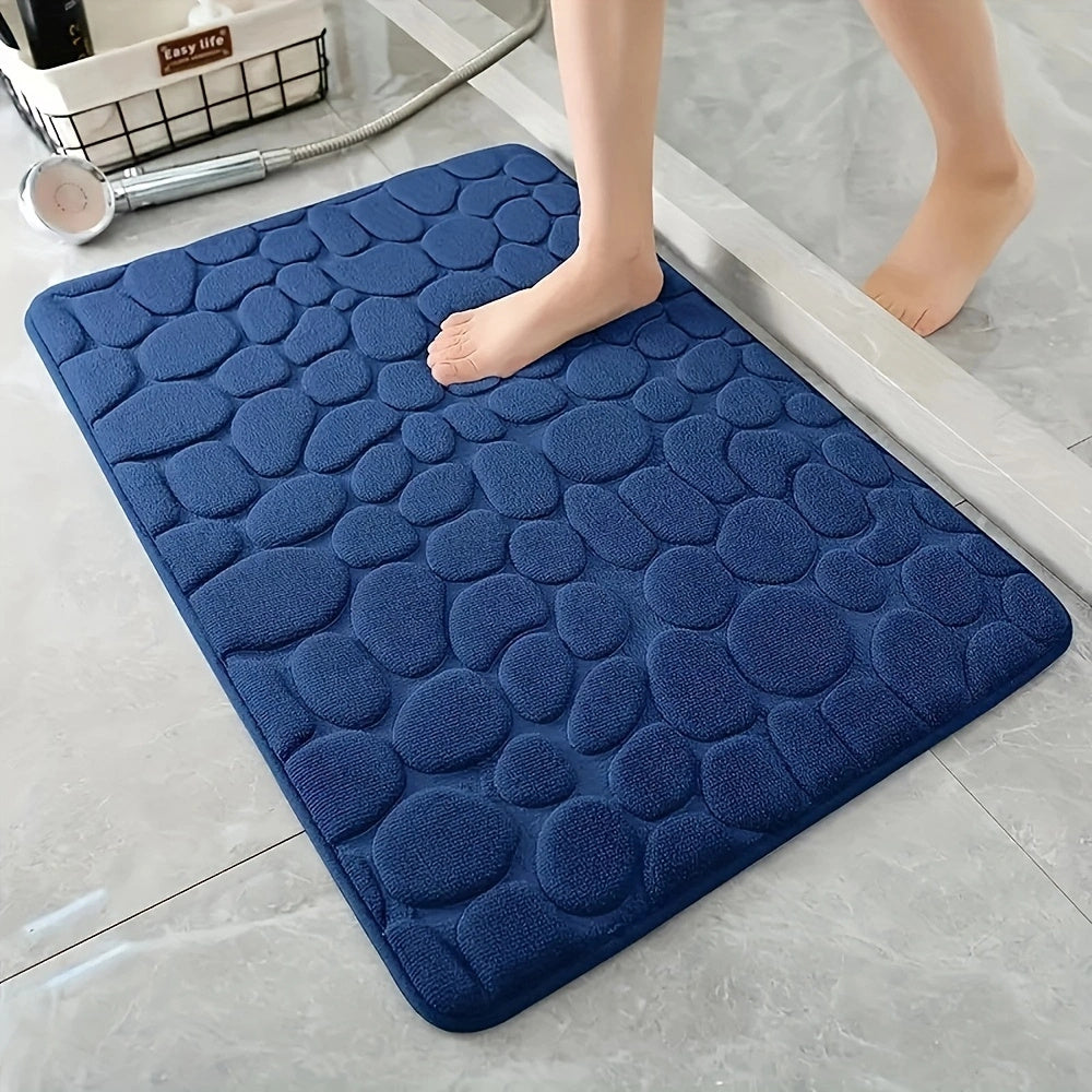 Blue textured bath mat on a bathroom floor with a person stepping onto it.