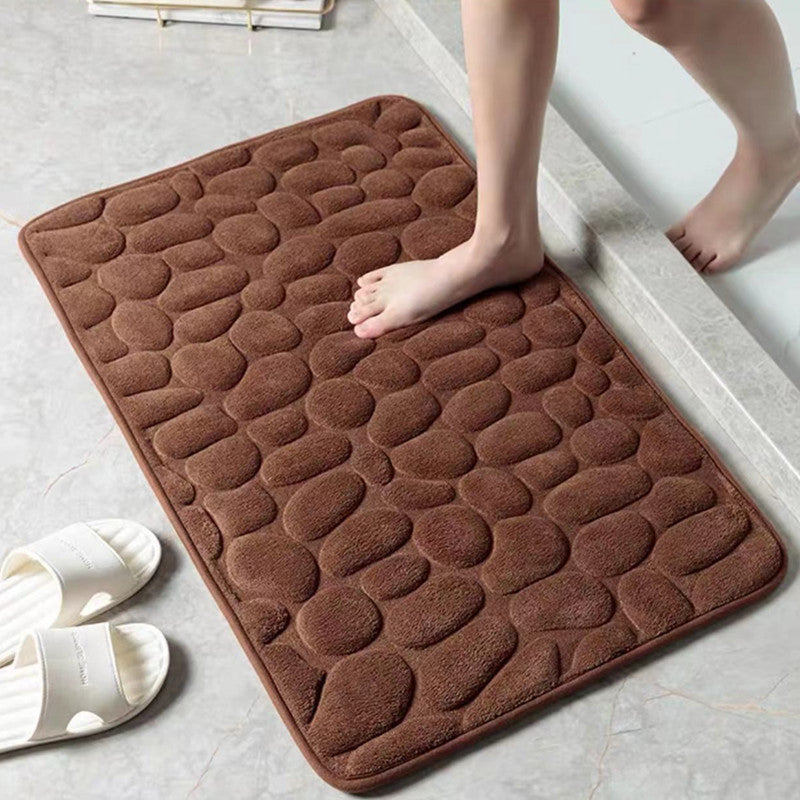 Brown textured bath mat on a bathroom floor with a person stepping onto it.
