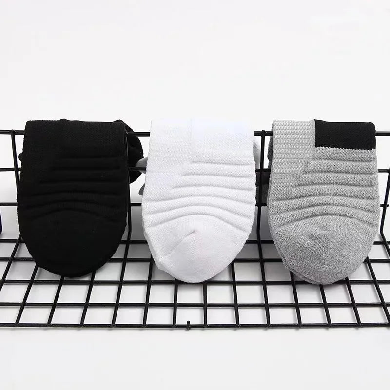Three pairs of socks in black, white, and gray on a wire rack.