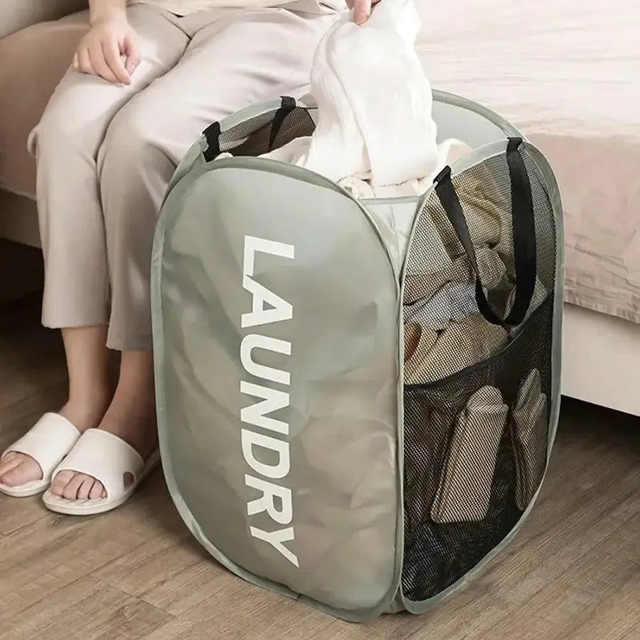 Person sitting on a couch with a large gray laundry bag filled with clothes.