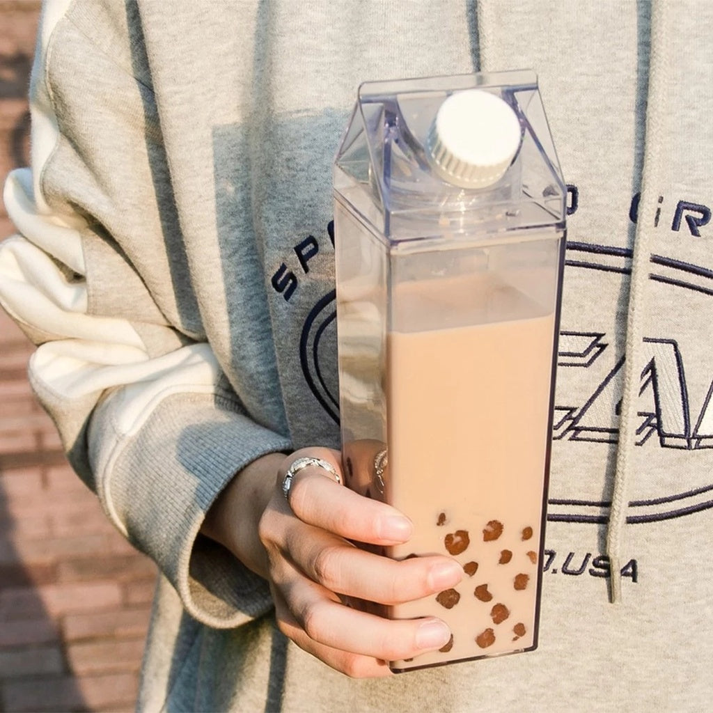 Person holding a carton of bubble tea with a neutral background