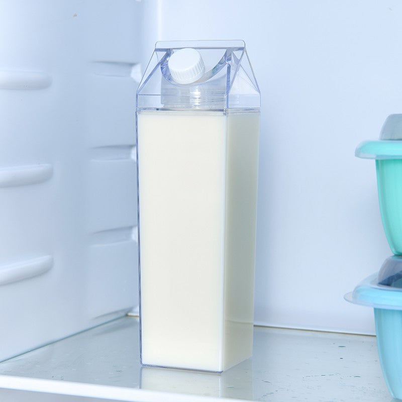 Clear container with milk inside an open refrigerator.