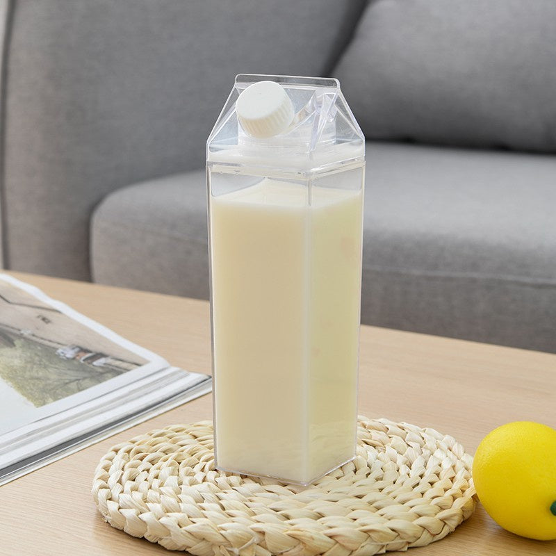 Carton-shaped container with liquid on a woven coaster with a lemon and magazine in the background.