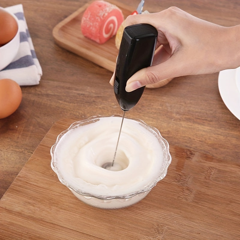 Hand using a kitchen tool to mix whipped cream in a glass bowl on a wooden table.