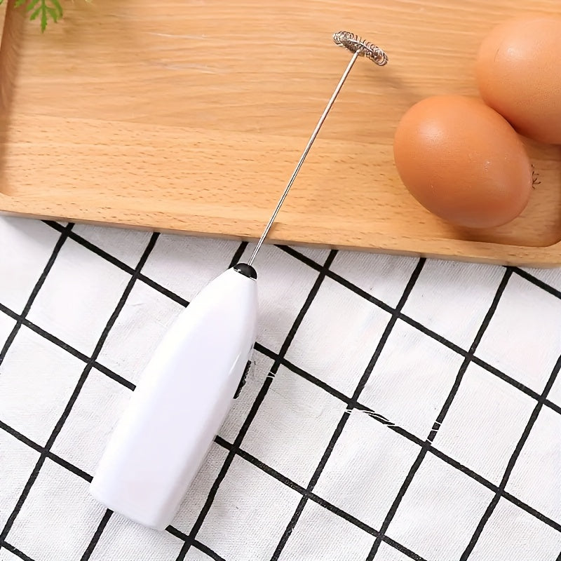 White milk frother with metal whisk on a wooden tray with eggs on a grid-patterned surface