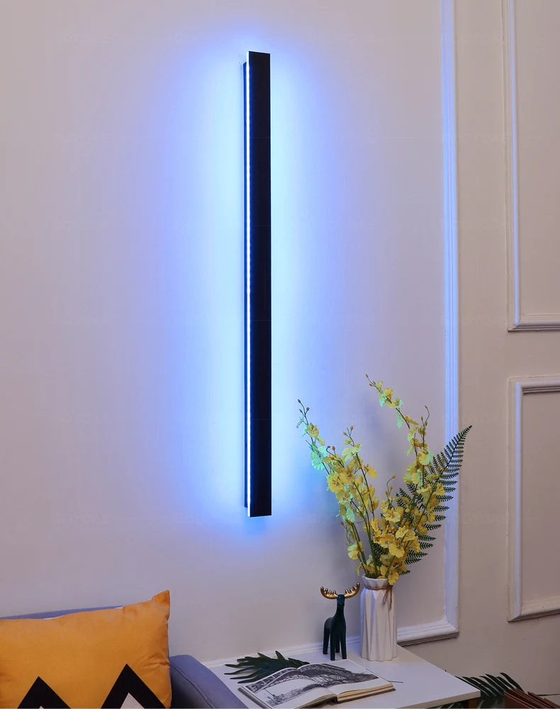Wall-mounted LED light fixture with a vase of flowers and books on a table in a room setting.