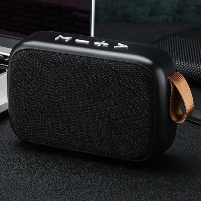 Black portable speaker with a brown strap on a dark surface