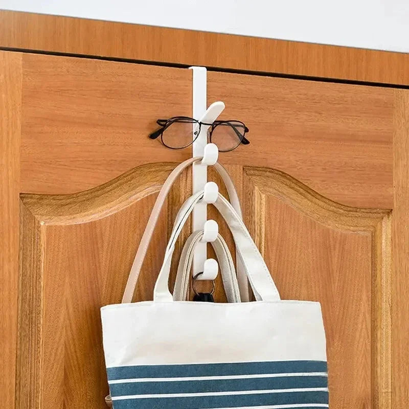 Over-the-door hook holding a tote bag and a pair of glasses on a wooden door.