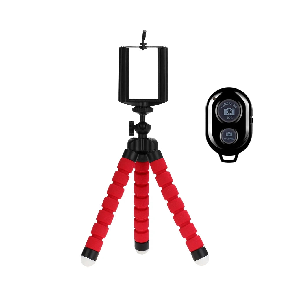 Red flexible tripod with black smartphone holder and remote control on a white background