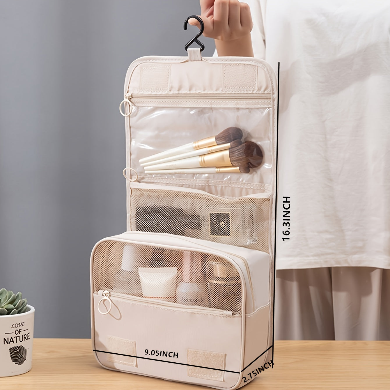Beige travel makeup organizer with brushes and products on a wooden surface.