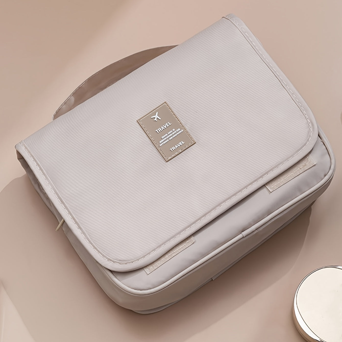 Light gray travel bag with a visible brand logo on a beige background
