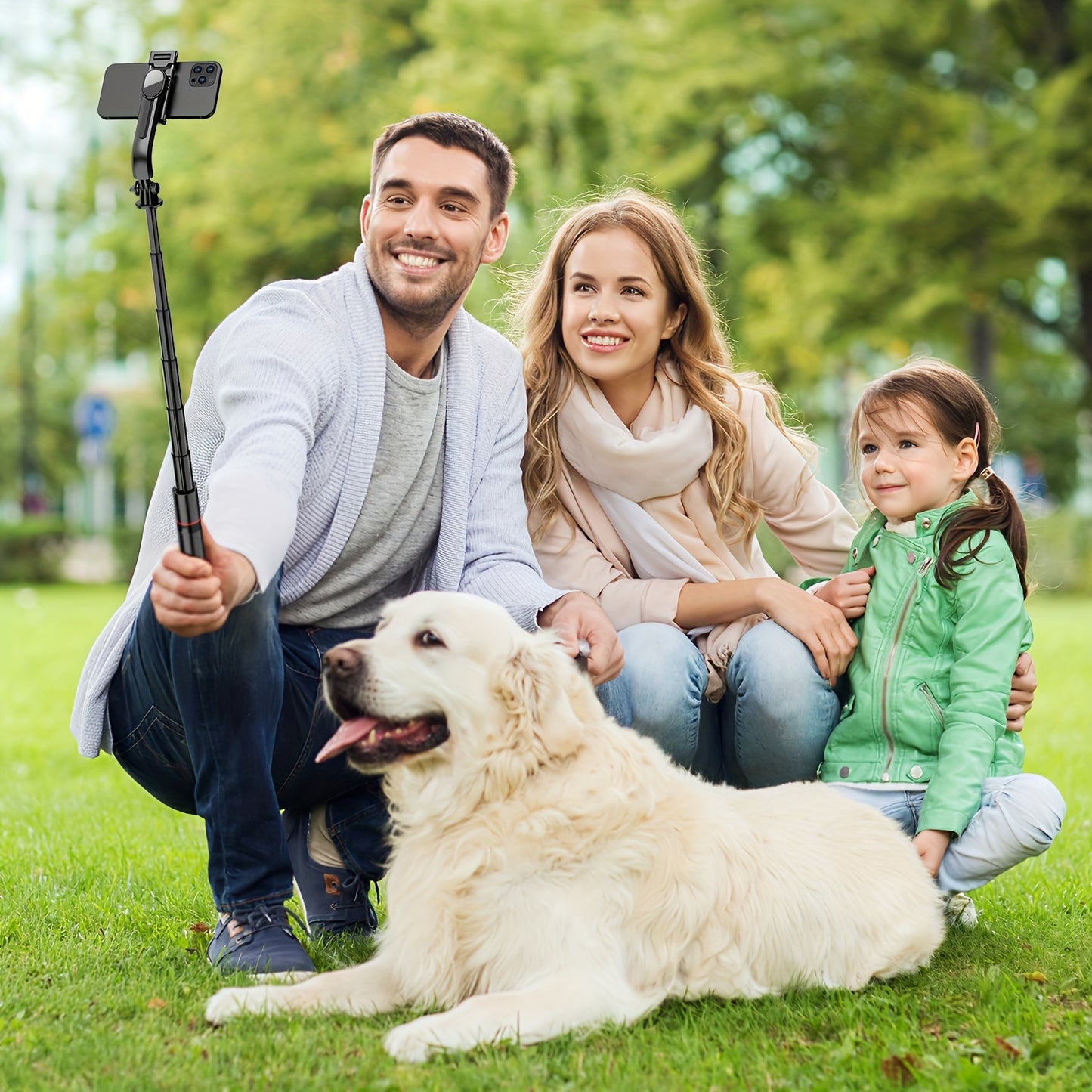 Family of three with a dog taking a selfie in a park