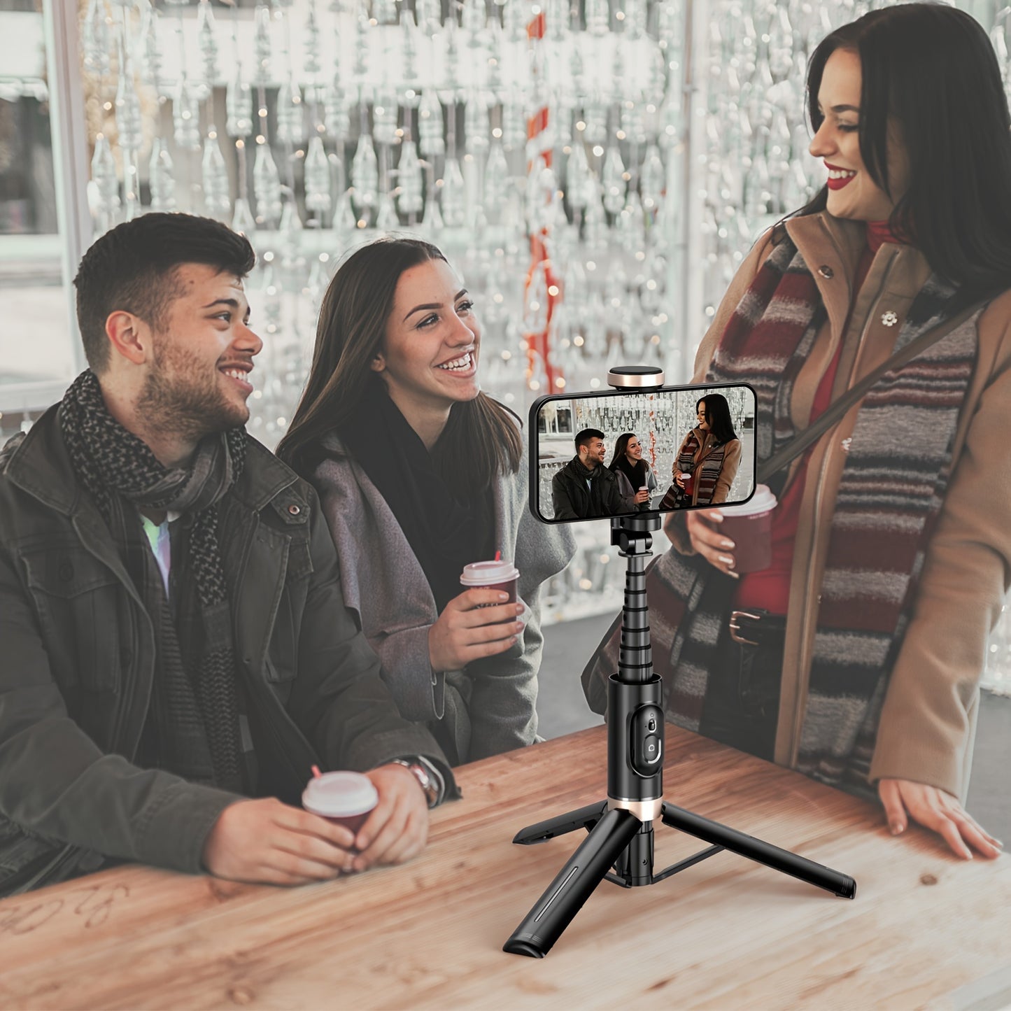 People sitting at a table with a smartphone on a tripod displaying a video call.