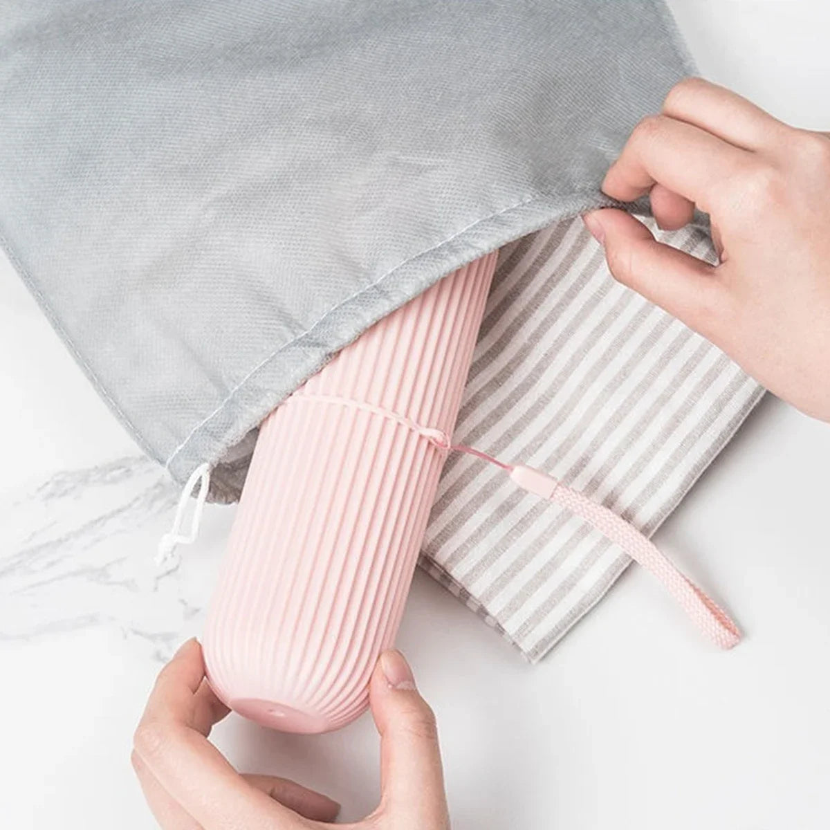 Pink ribbed product being removed from a gray cloth bag on a light surface.