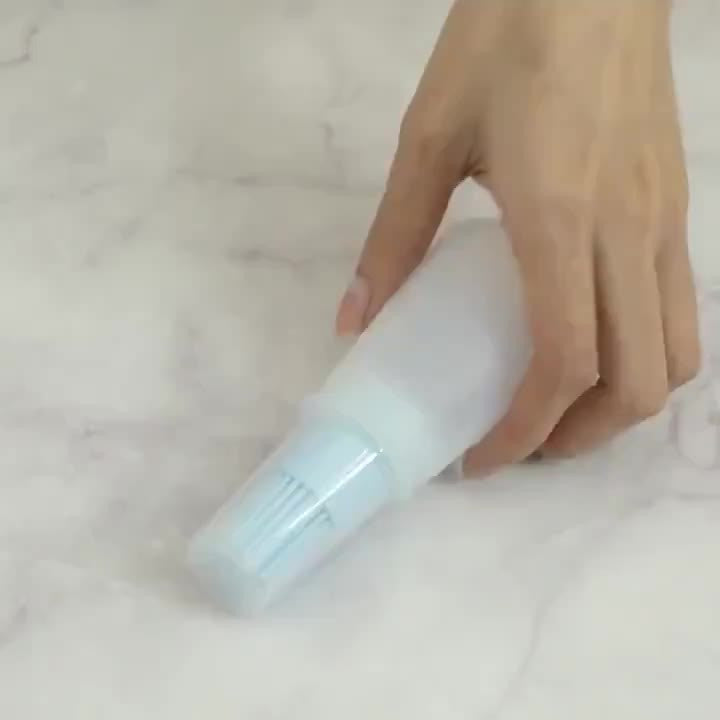 Hand holding a white spray bottle on a light-colored surface